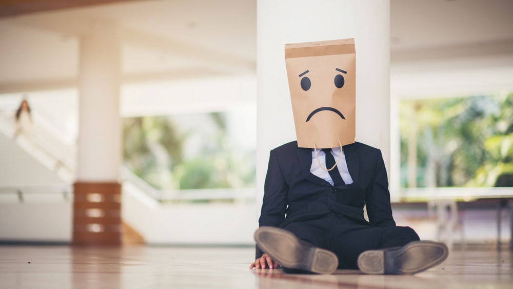 sad entrepreneur with no career growth wearing a bag over his head